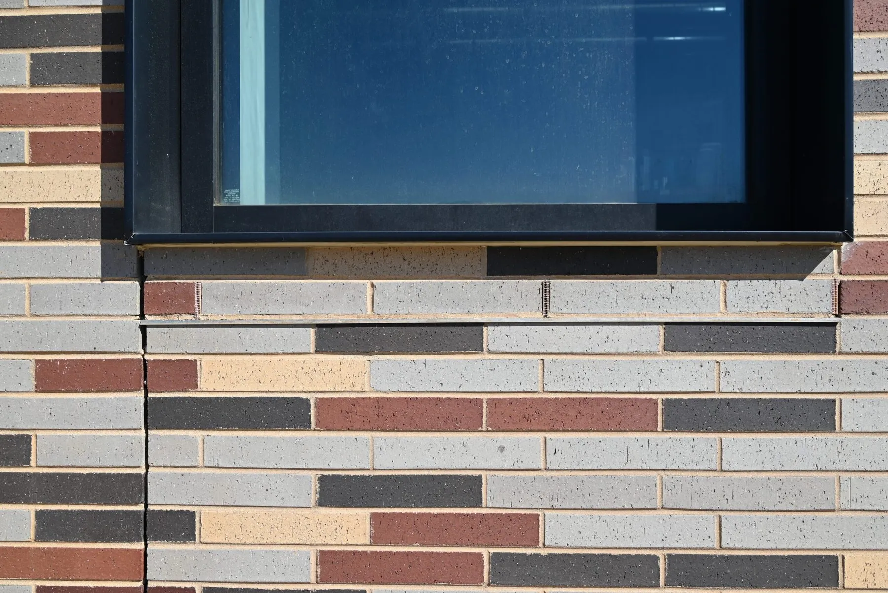 Close detail of the graduated brick blend at a window head, showing platinum, red, and sand colored units in a random running bond