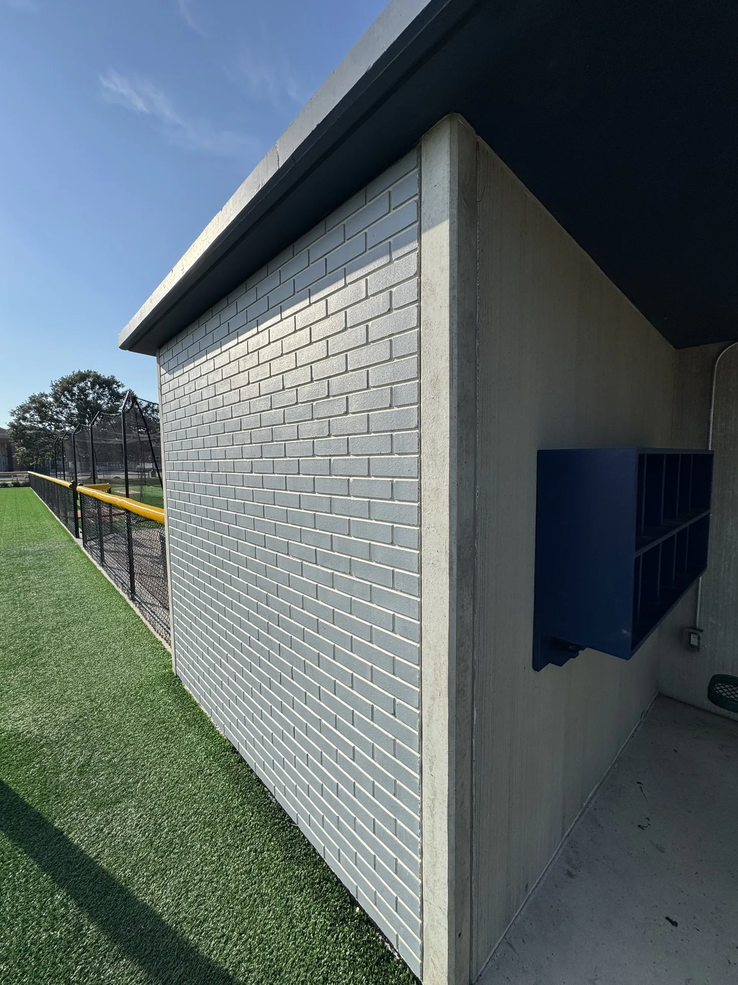 Corner of a Field 32 dugout showing the cast-in cubbies at the open end and the light blue brick pattern turning the corner in one piece